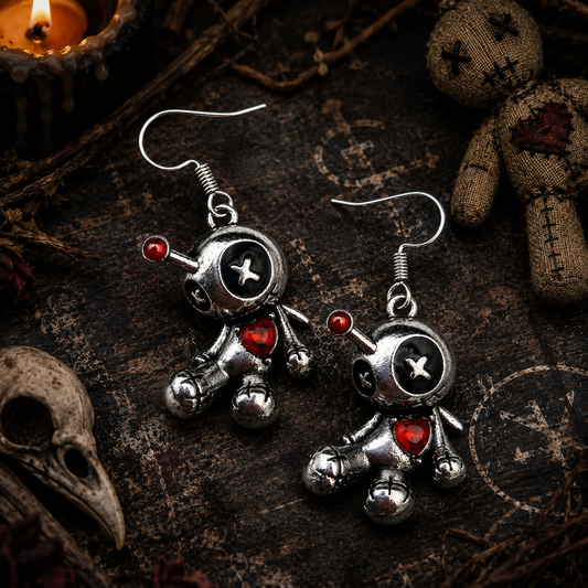 Silver voodoo doll earrings with button eyes and a red heart accent—creepy yet cute.
